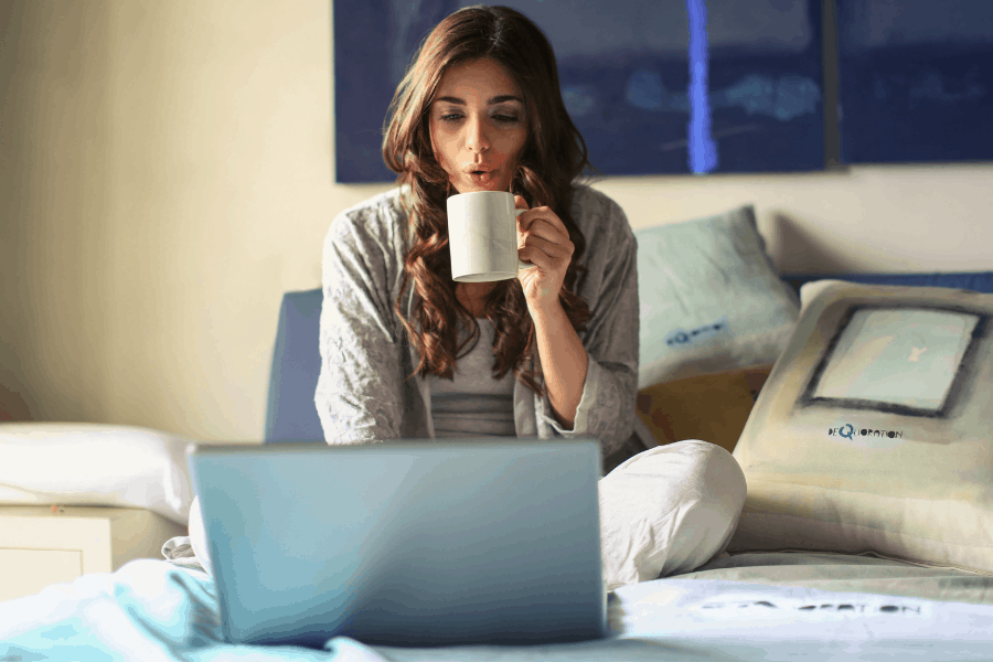 woman sipping coffee while typing on a laptop